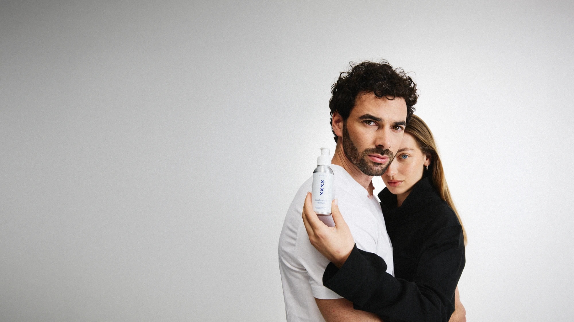 Hombre sosteniendo Fundamental Hydrogel abrazado por una mujer, campaña de XYXY