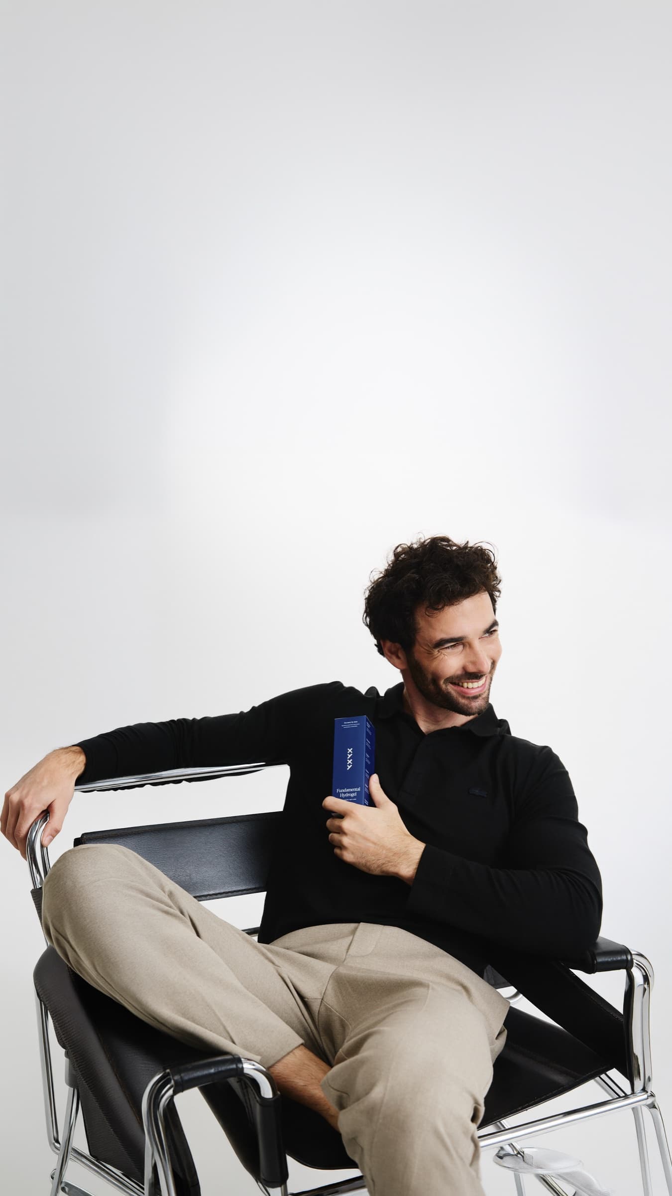 Hombre sonriendo en un sillón con Fundamental Hydrogel en la mano