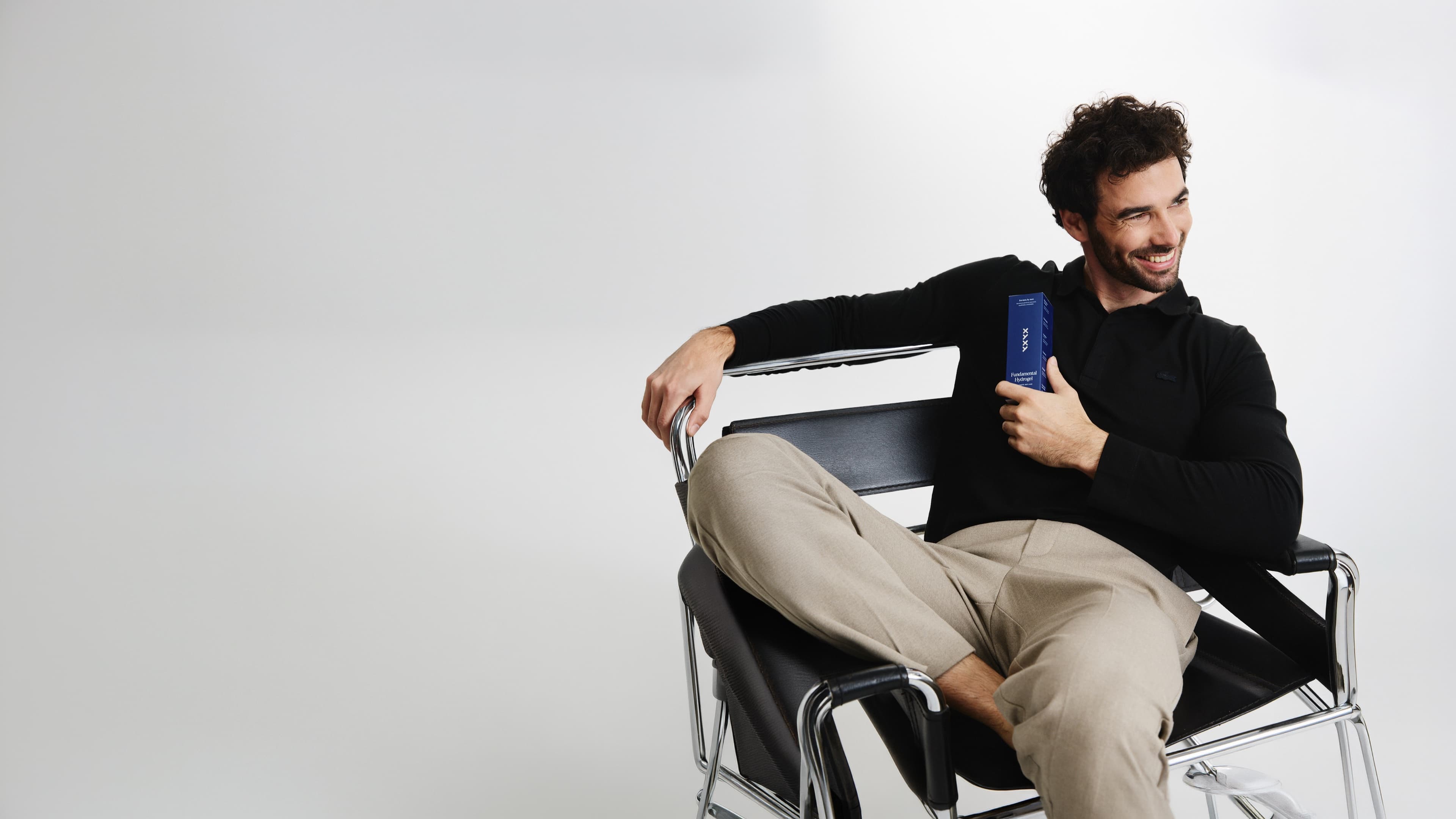 Hombre sonriendo en un sillón con Fundamental Hydrogel en la mano
